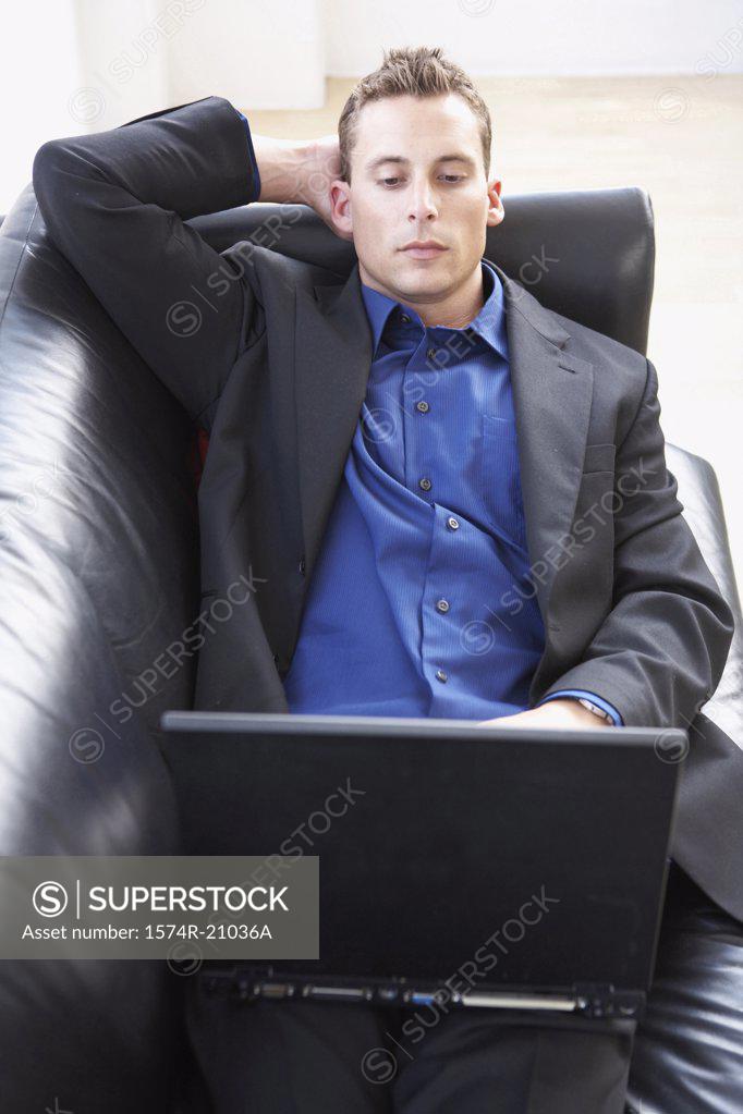 Stock Photo: 1574R-21036A High angle view of a businessman reclining on a couch and using a laptop
