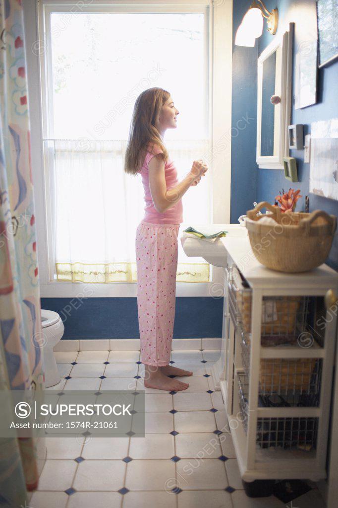Stock Photo: 1574R-21061 Side profile of a teenage girl standing in front of a mirror in the bathroom
