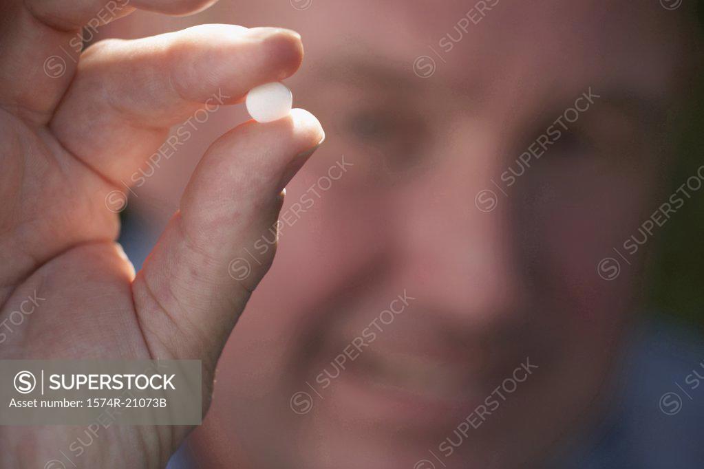 Stock Photo: 1574R-21073B Close-up of a mature man showing a pill