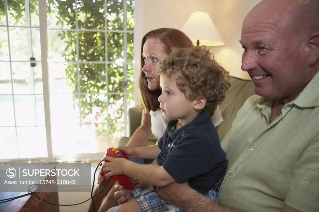 Side profile of a boy sitting with his grandparents and playing a video game