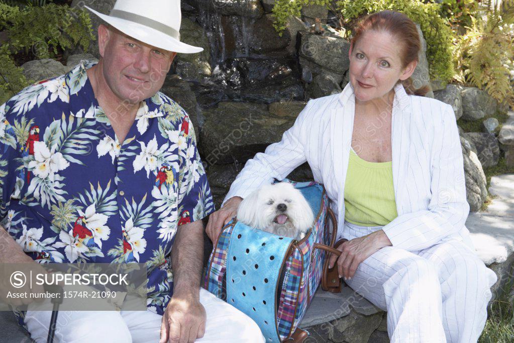 Stock Photo: 1574R-21090 Close-up of a mature couple sitting in a garden with a dog in a bag