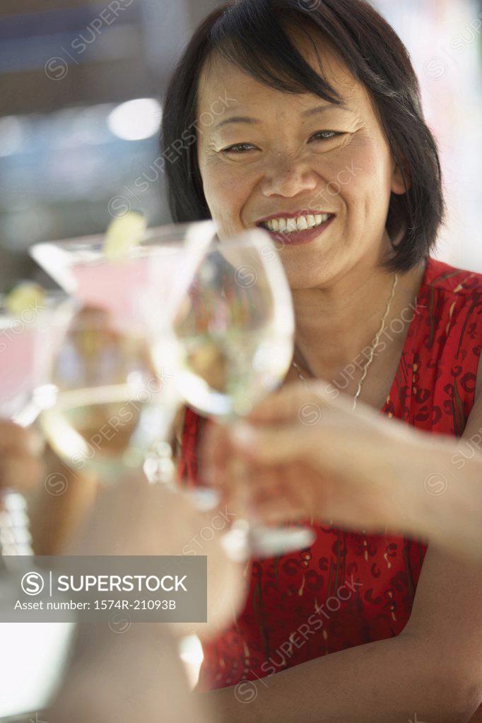 Stock Photo: 1574R-21093B Human hands toasting with glasses and a mature woman smiling in the background