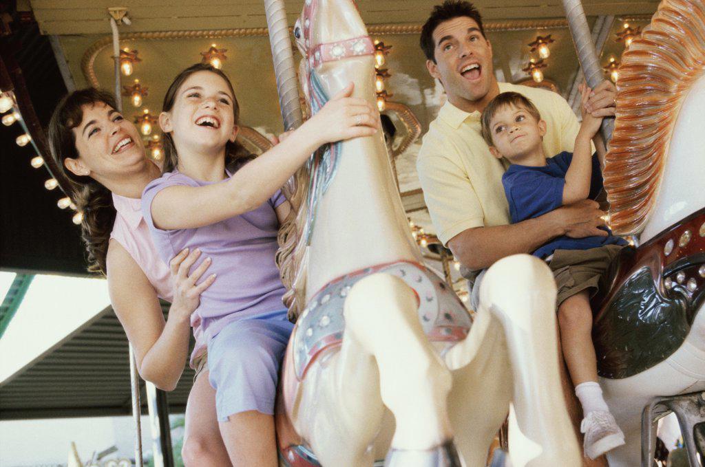 Low angle view of parents with their son and daughter on a carousel