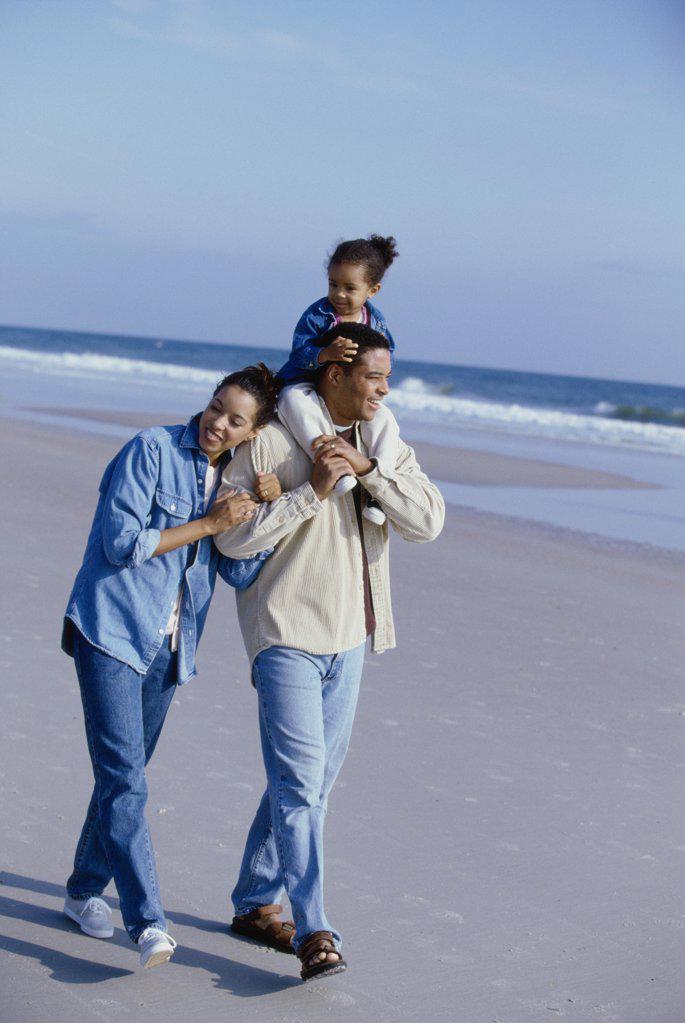 Parents smiling with their daughter on the beach