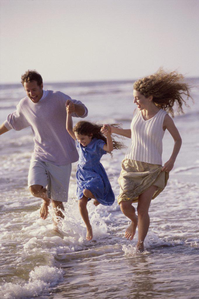 Parents and their daughter running on the beach