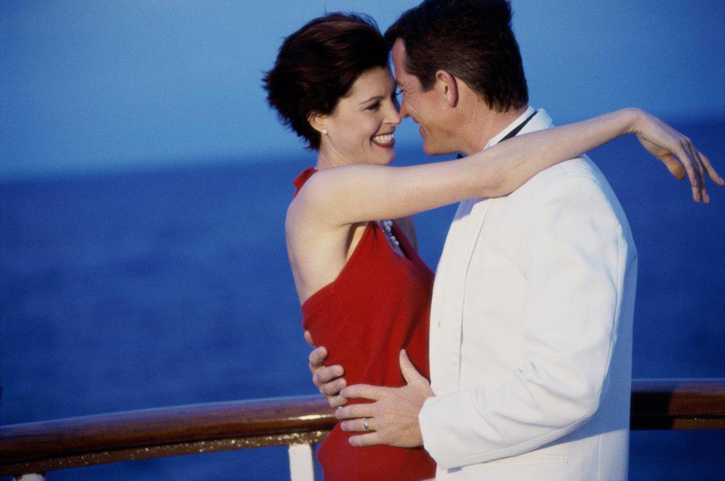 Side profile of a young couple embracing on the deck of a cruise ship