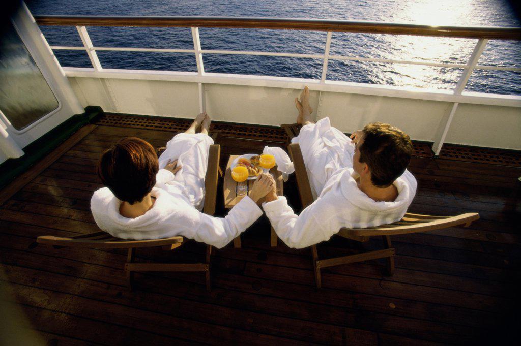 High angle view of a mid adult couple sitting in deck chairs on a cruise ship