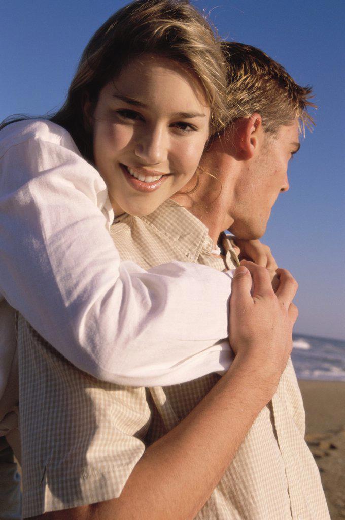 Portrait of a teenage girl hugging a young man