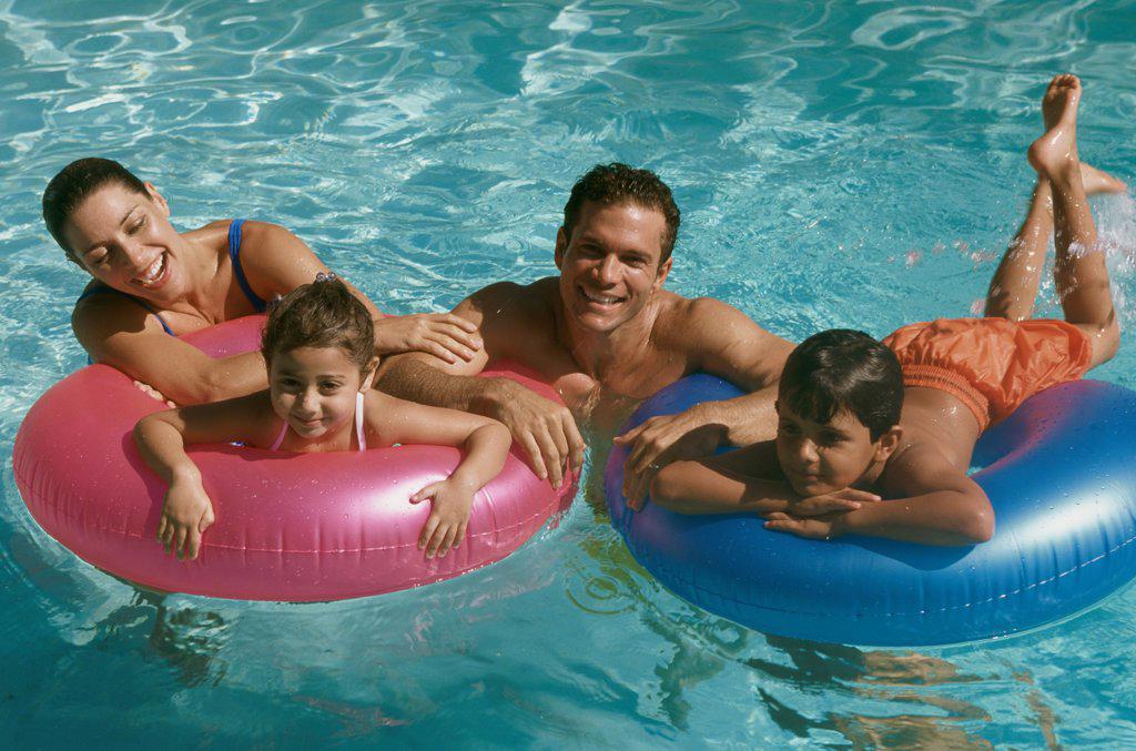 Portrait of a young couple in a swimming pool with their son and daughter