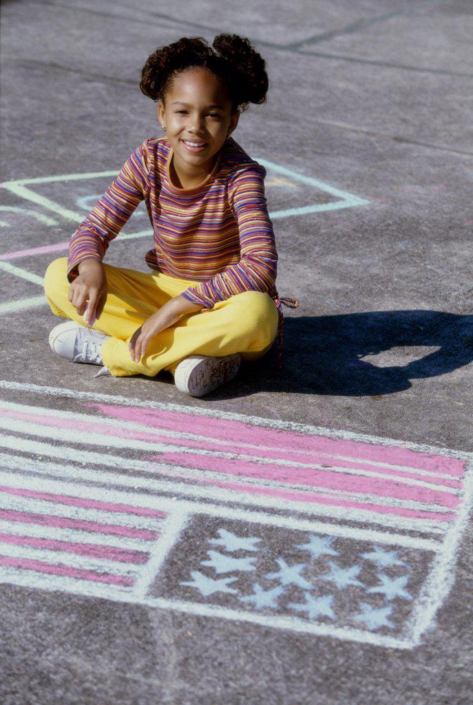 Portrait of a girl drawing an American flag on the ground with chalk