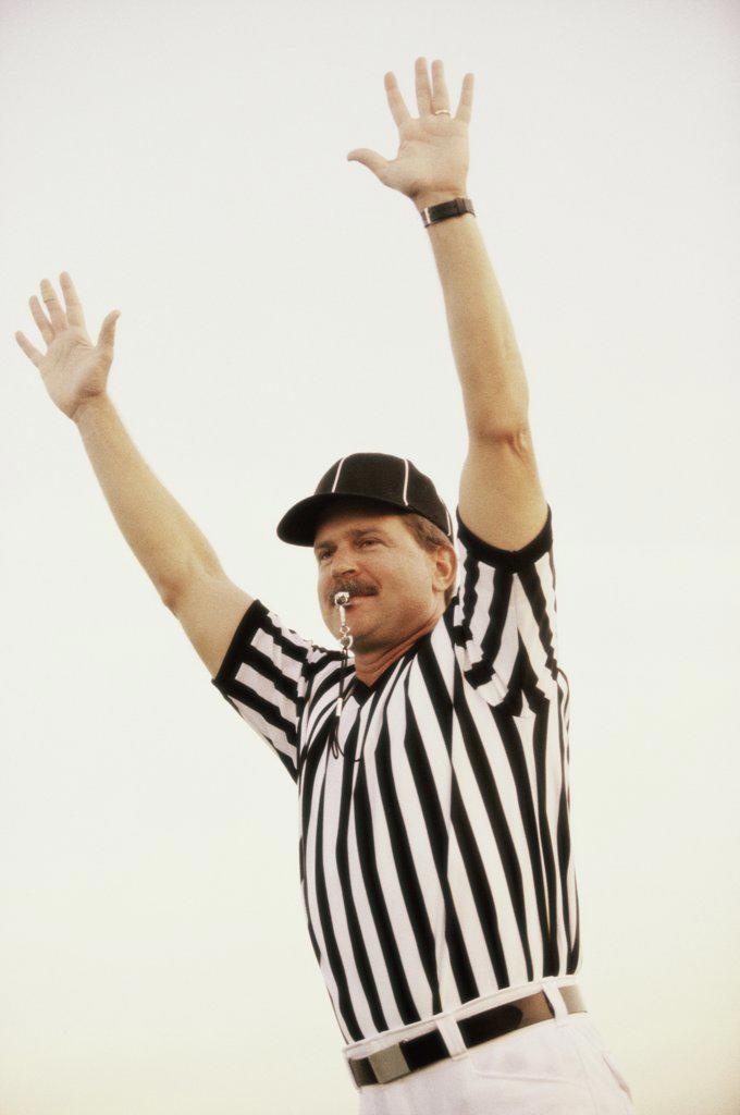 Football referee whistling with his arms raised