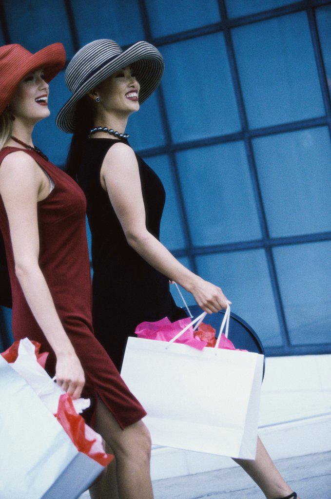 Side profile of two young women walking with shopping bags
