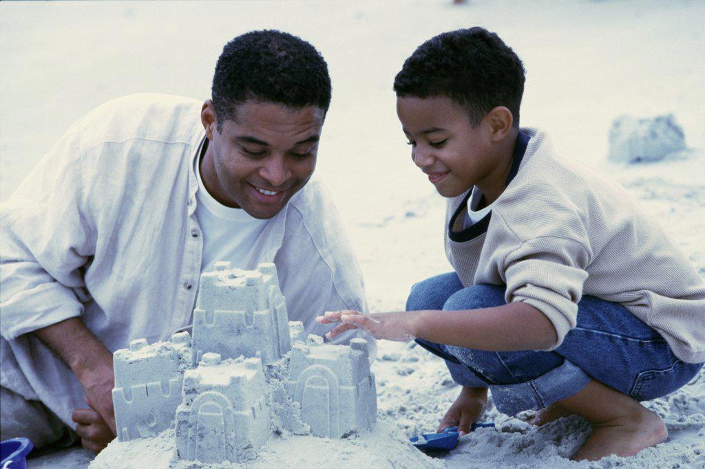 Father and his son making sand castles on the beach
