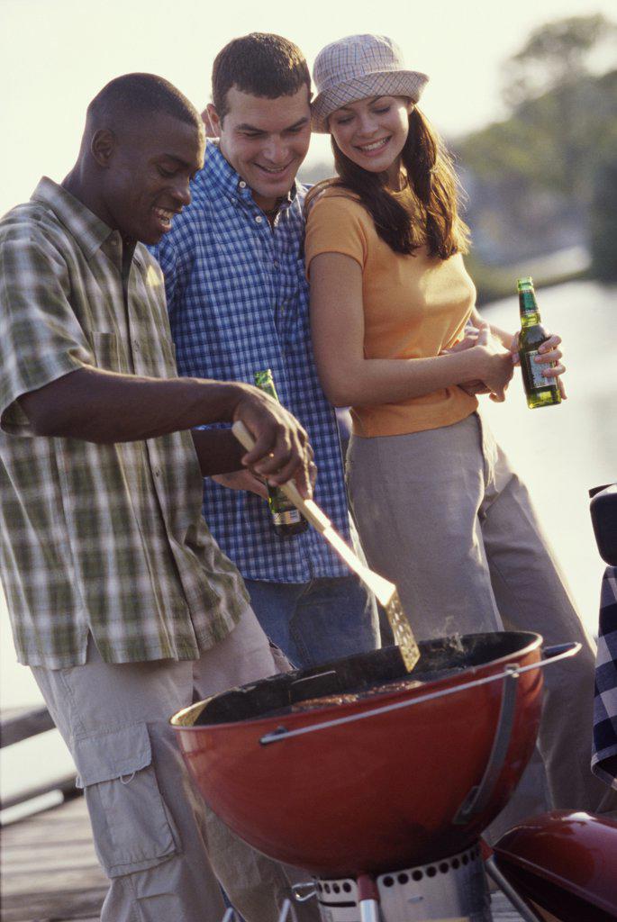 Two young men and a young woman at a barbecue