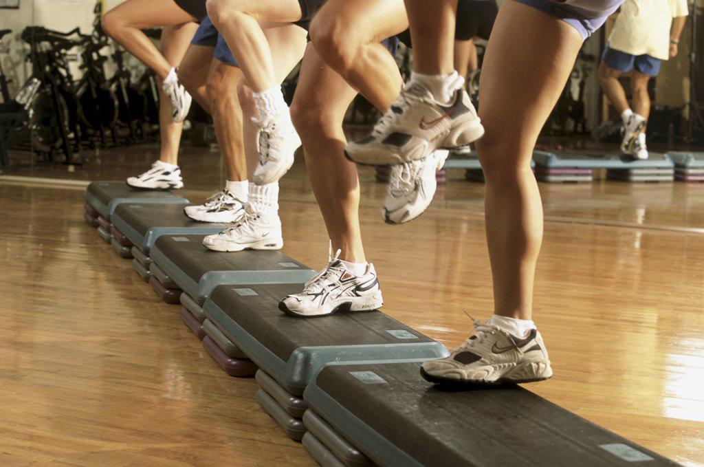Low section view of a group of people exercising in a step aerobics class