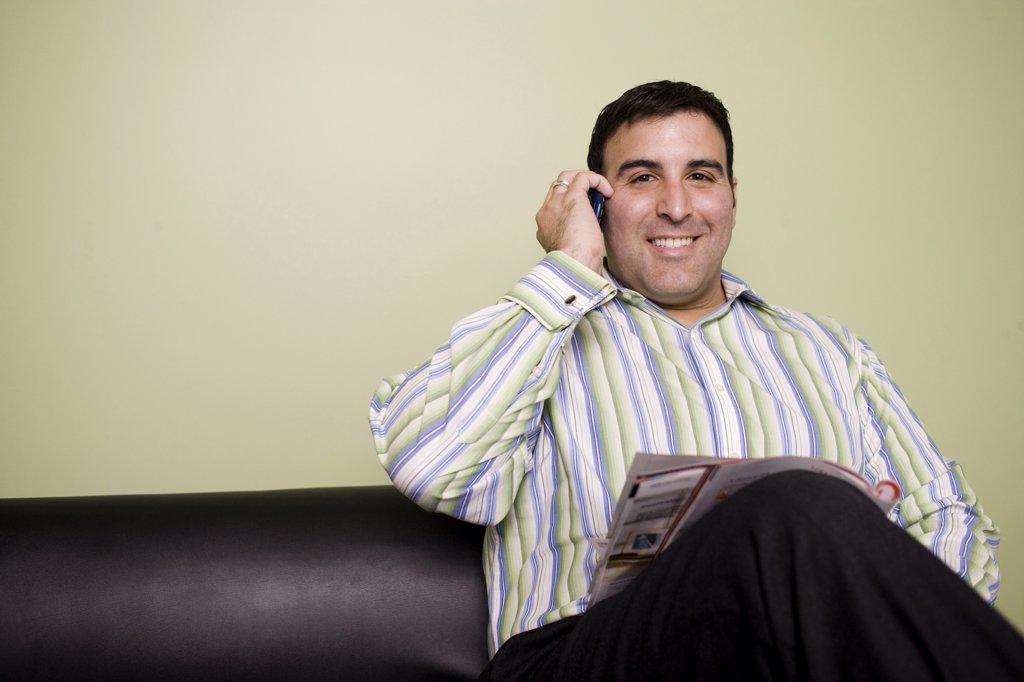 Portrait of a businessman sitting on a couch talking on a mobile phone