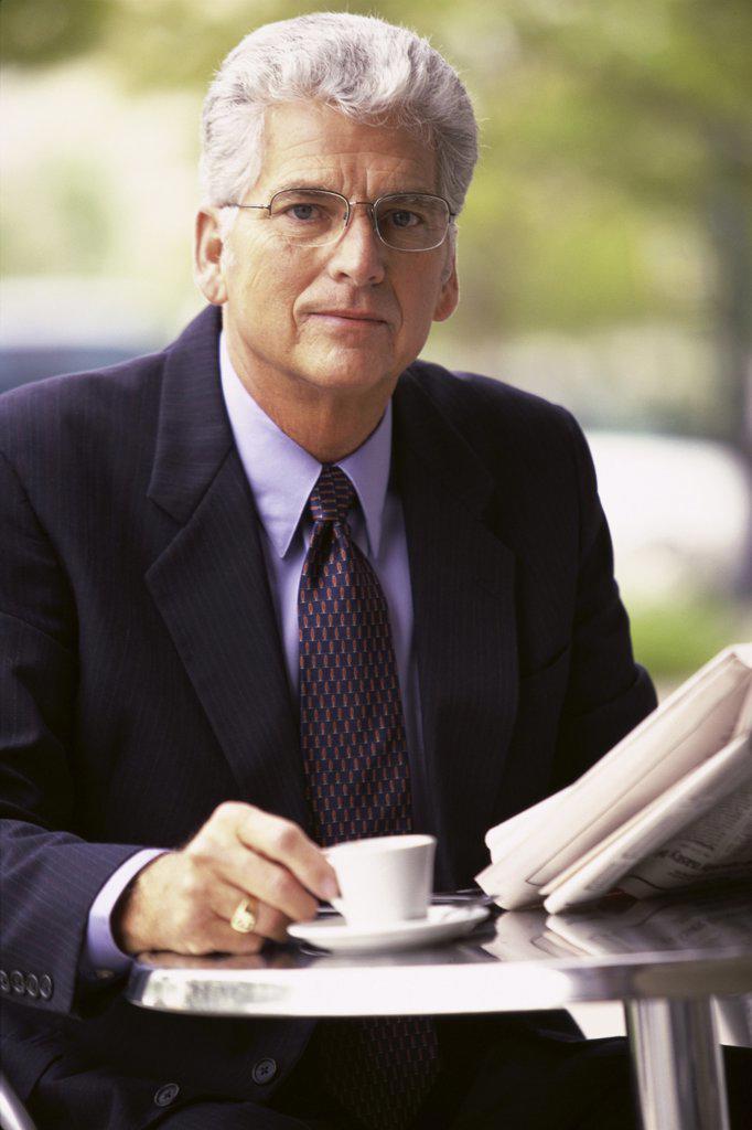 Portrait of a businessman holding a newspaper and a cup of coffee