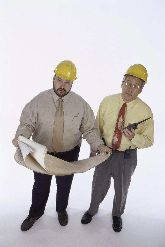 Two foremen holding walkie-talkies and blueprints