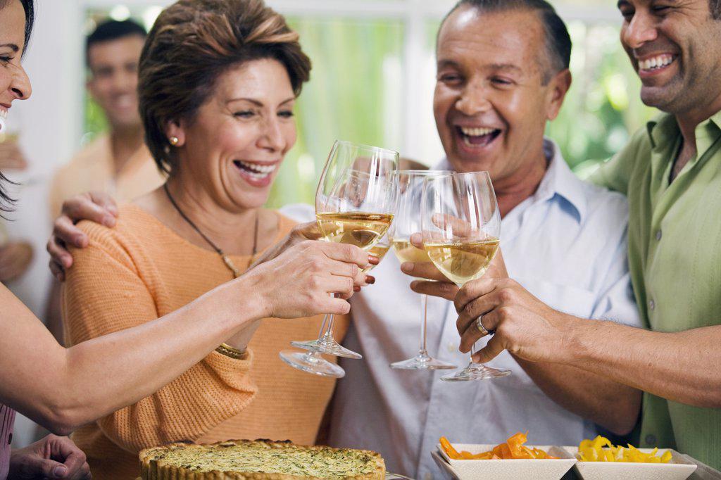 Close-up of two mature couples toasting with wineglasses and smiling