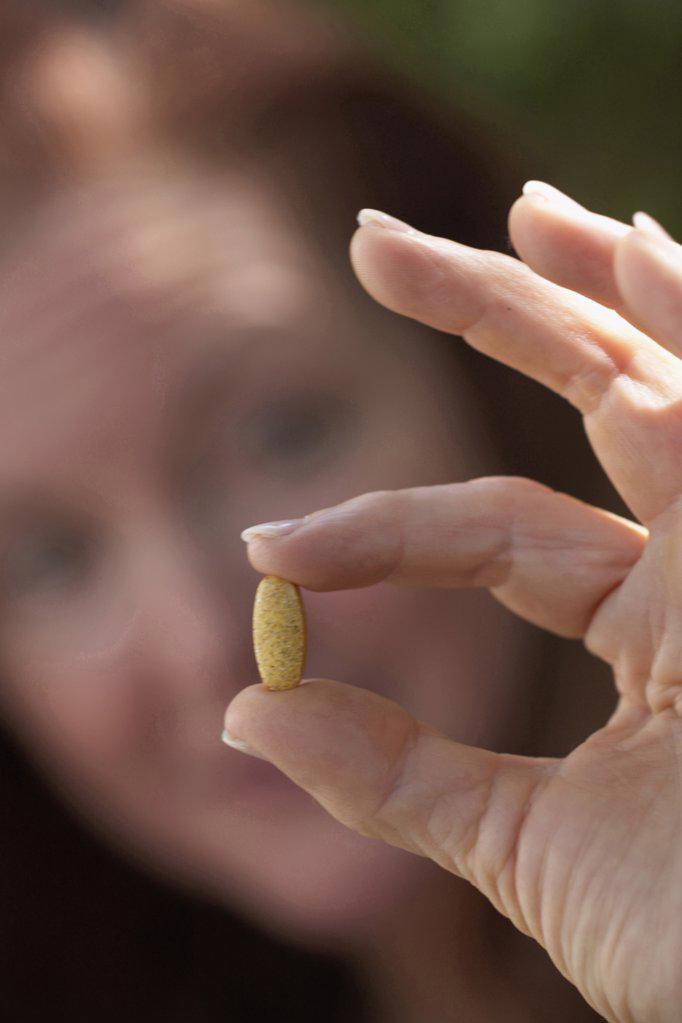 Close-up of a mature woman showing a pill