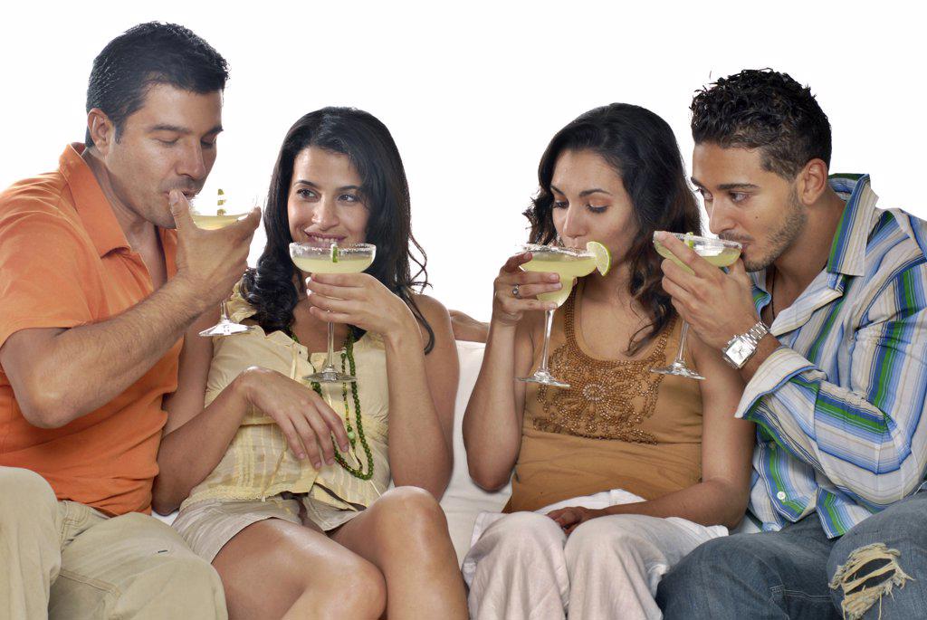Mid adult couple and a young couple sitting on a couch and drinking margaritas