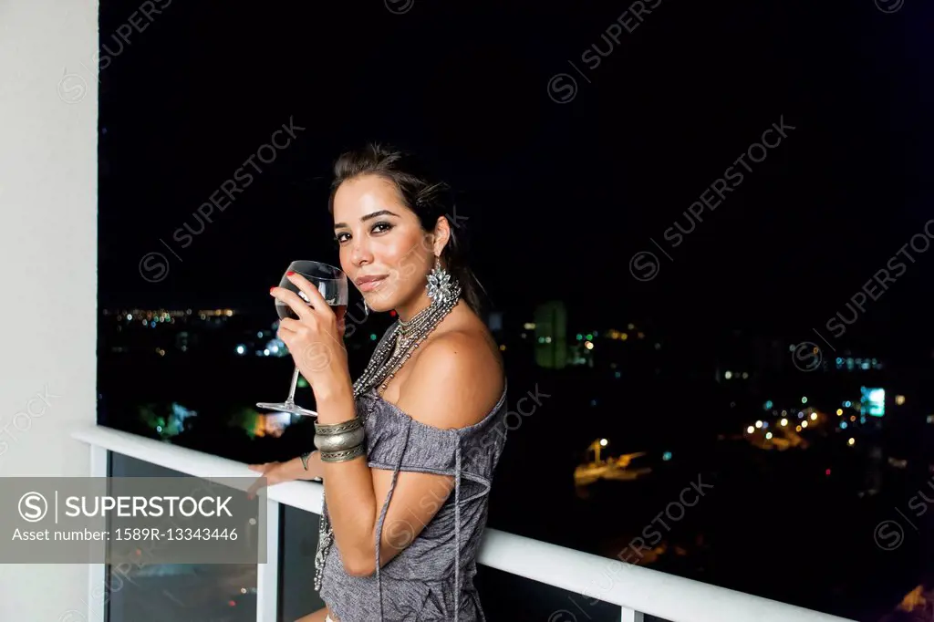 Woman drinking wine on urban balcony