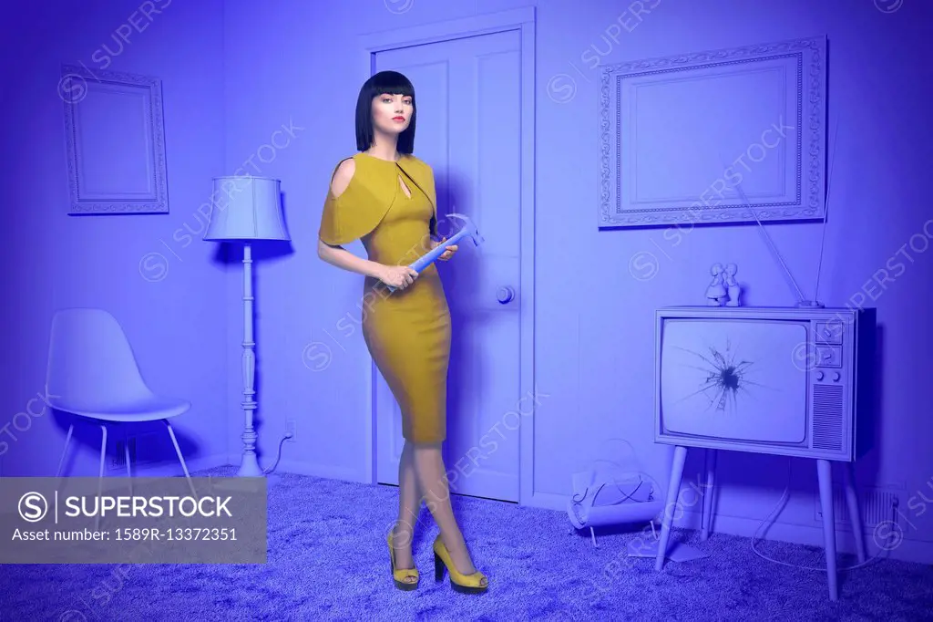 Caucasian woman in purple old-fashioned livingroom holding hammer