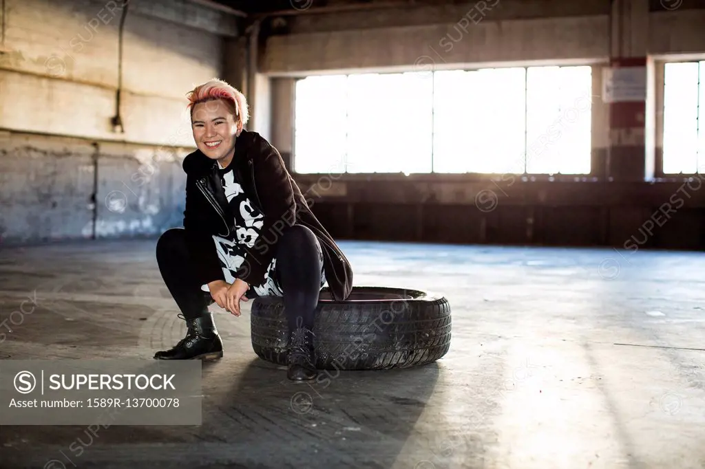 Portrait of smiling androgynous Asian woman sitting on wheel