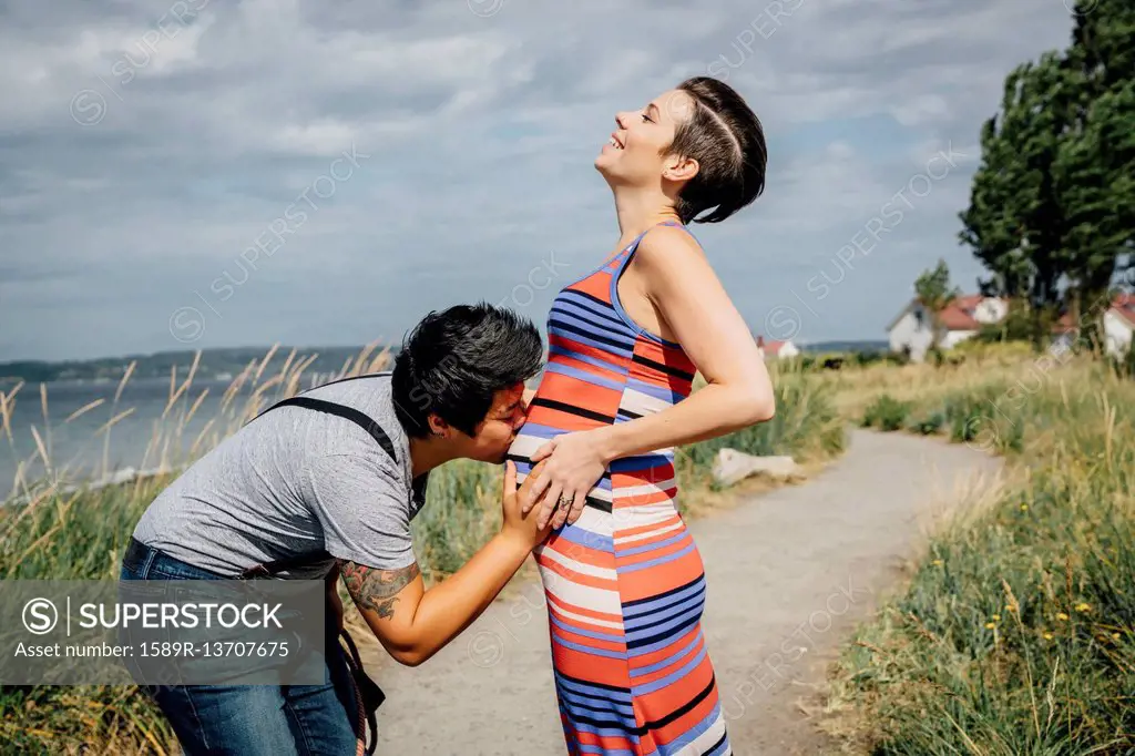 Woman kissing belly of expectant mother