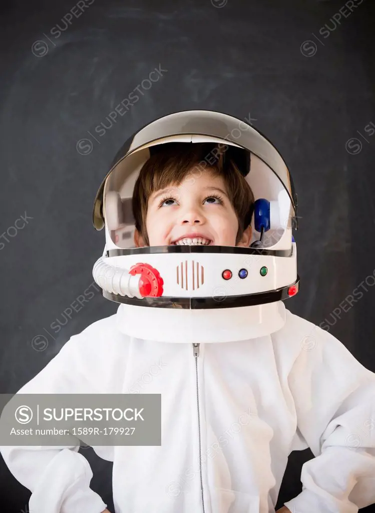 Hispanic boy wearing space helmet in classroom