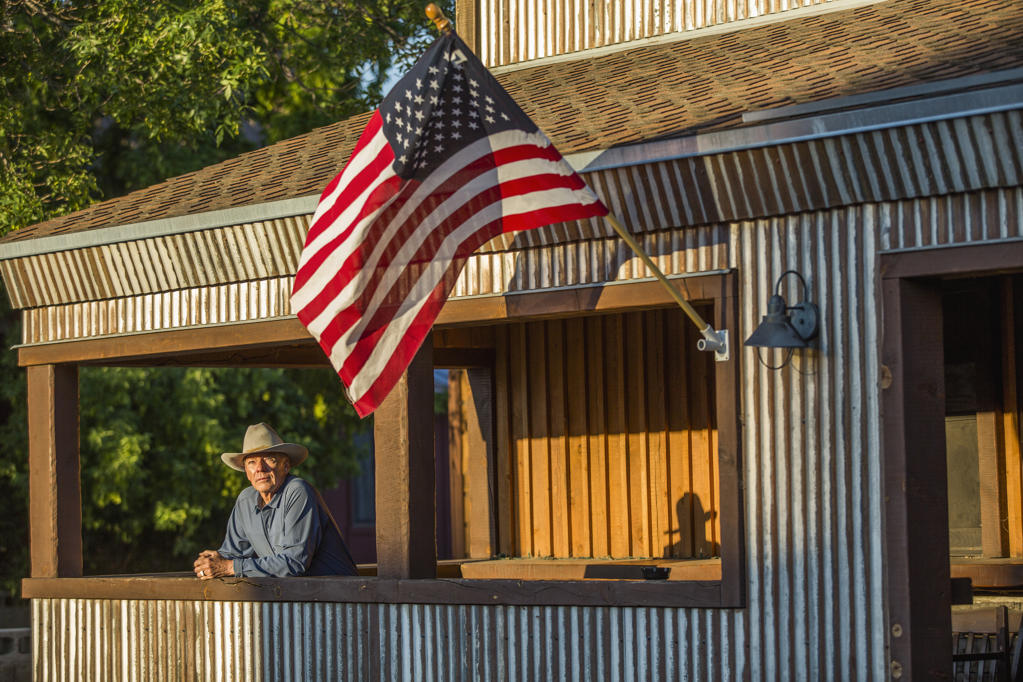 Serious Caucasian farmer on porch with American flag