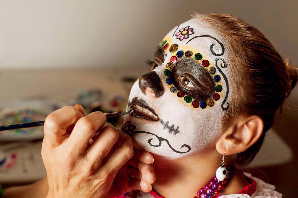Girl having face painted for Dia de los Muertos