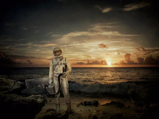 Caucasian astronaut standing on beach at sunset