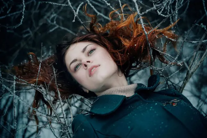 Serious Caucasian woman laying on icy branches