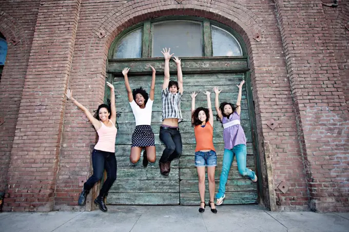 Friends jumping on urban sidewalk