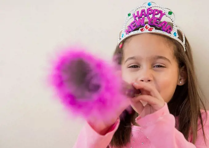 Hispanic girl using noise maker at New Years' party
