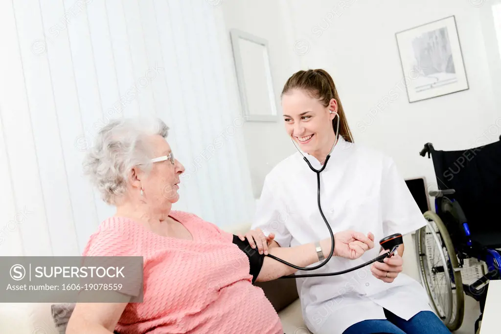 Elderly senior woman with young doctor having medical care at home.