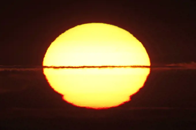 France, Normandy. Closeup of the distorted sun shortly before sunset.