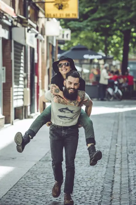 Young man carrying his girlfriend on his back in an urban environment