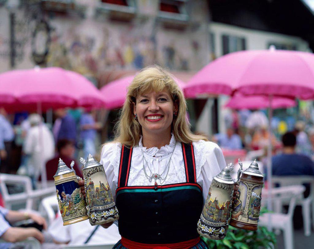Beer Garden (Biergarten) / Woman in Baverian Costume (Dirndl) holding Beer Steins , Mittenwald, Baveria, Germany