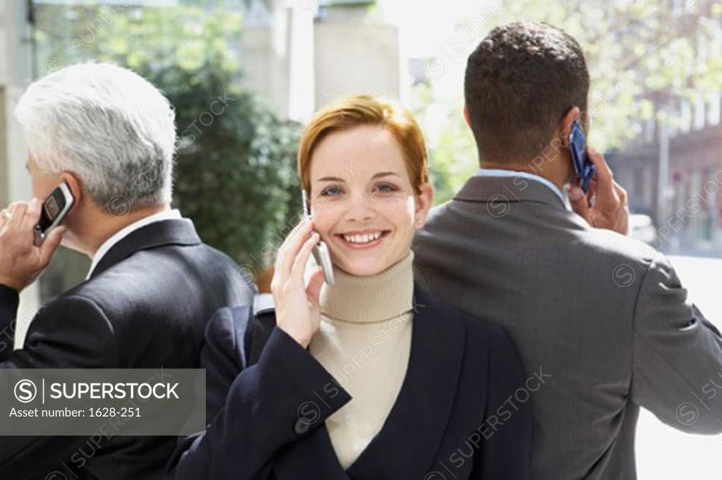 Stock Photo: 1628-251 Portrait of a businesswoman with two businessmen talking on mobile phones