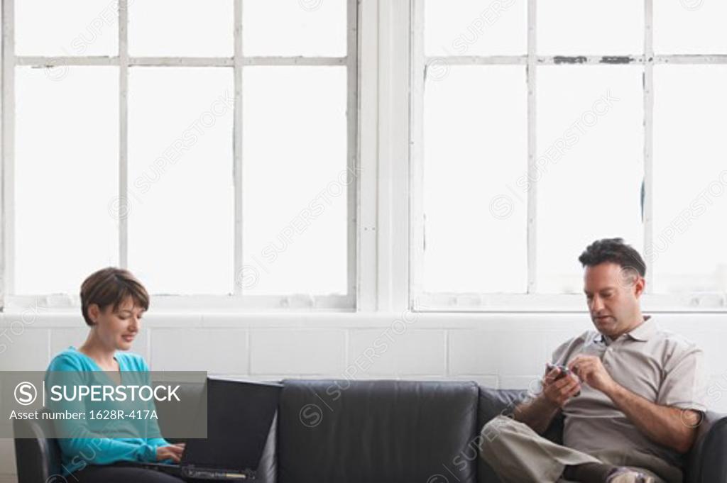 Stock Photo: 1628R-417A Businesswoman working on a laptop with a businessman using a PDA