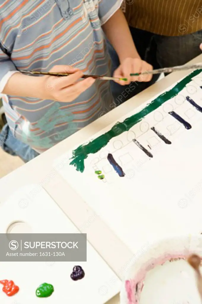 Mid section view of a boy holding a paint brush