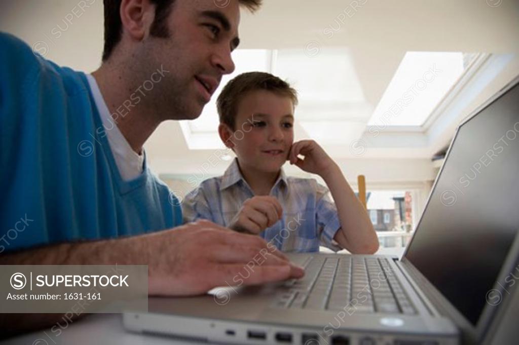 Stock Photo: 1631-161 Close-up of a young man using a laptop with his son standing beside him