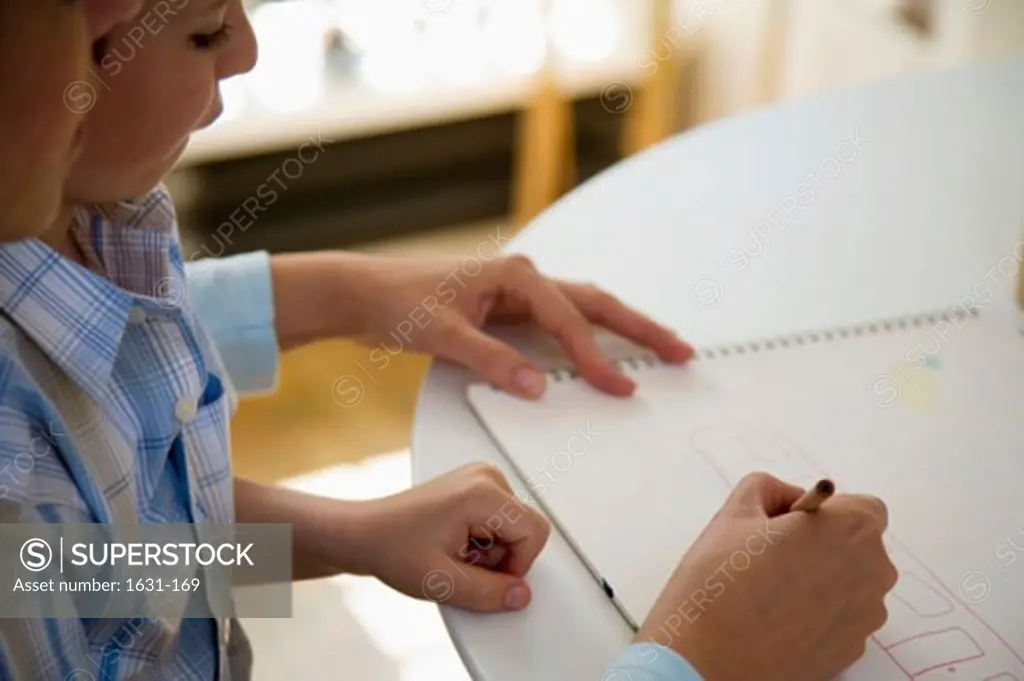 Close-up of a young woman teaching her son to draw