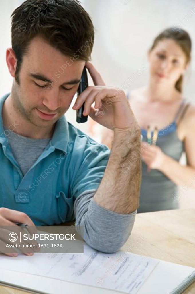 Stock Photo: 1631-182A Close-up of a young man using a mobile phone with a young woman standing behind him