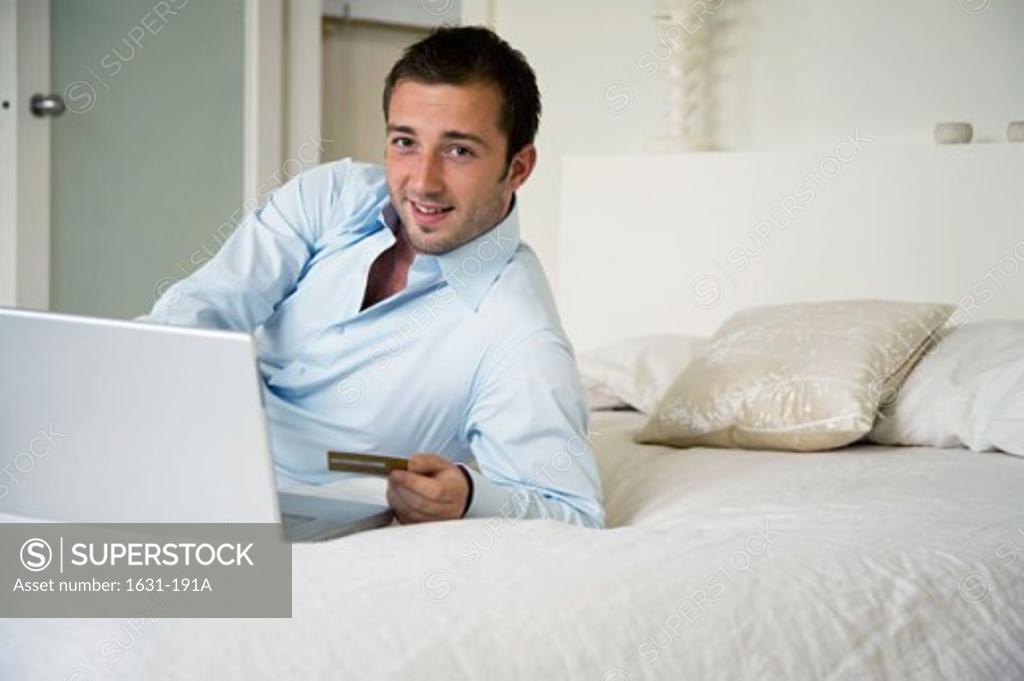 Stock Photo: 1631-191A Portrait of a young man using a laptop and holding a credit card