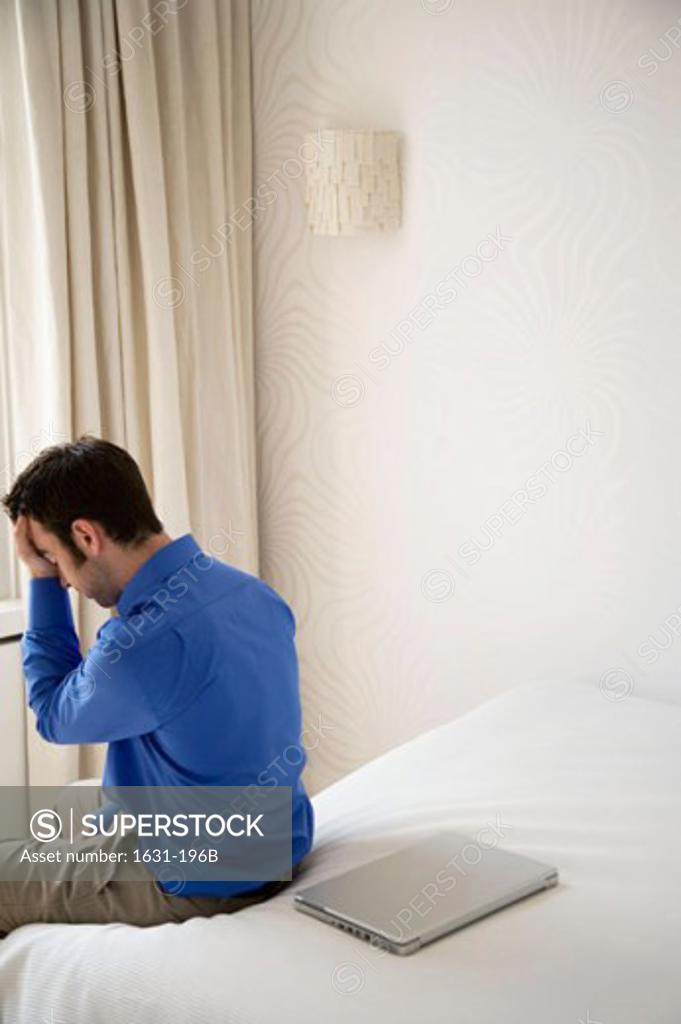 Stock Photo: 1631-196B Rear view of a young man sitting on the bed