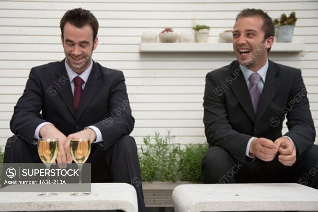 Stock Photo: 1631-213A Close-up of two businessmen sitting on a ledge and smiling