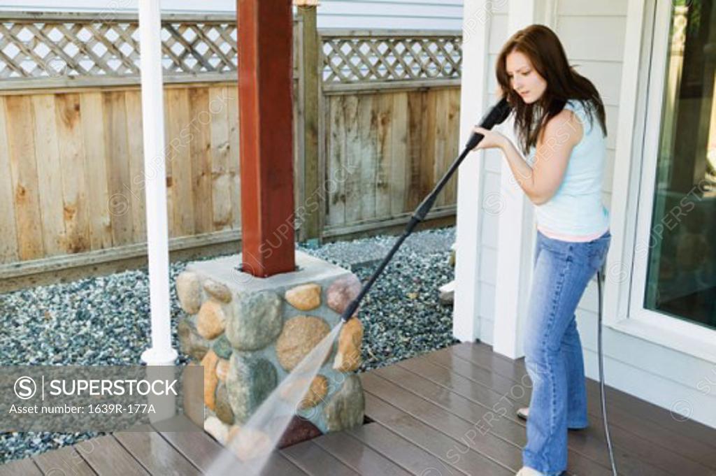 Stock Photo: 1639R-177A Side profile of a young woman cleaning the porch of her house